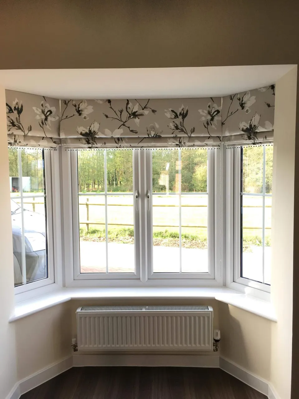 Shaped patterned valance across the top of a bay window above a radiator