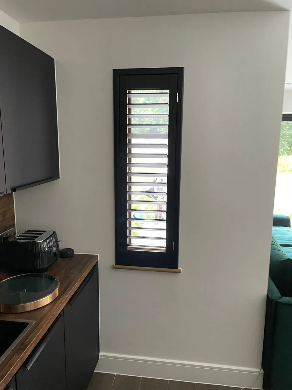 Dark plantation shutters on a slim window beside kitchen worktops
